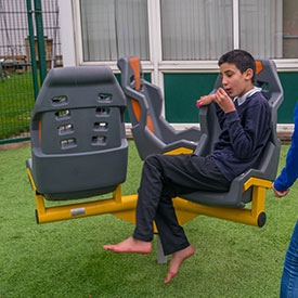 Boy riding on a roundabout with inclusive seats